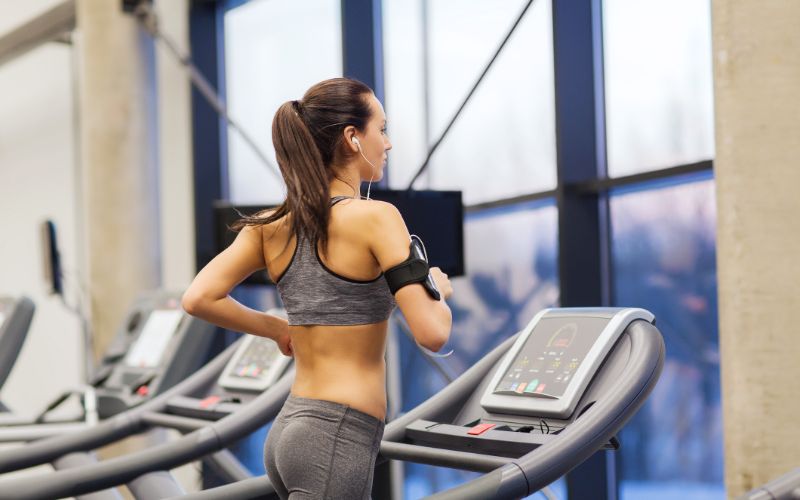 npl-supplements-woman-with-earphones-exercising-on-treadmill-min