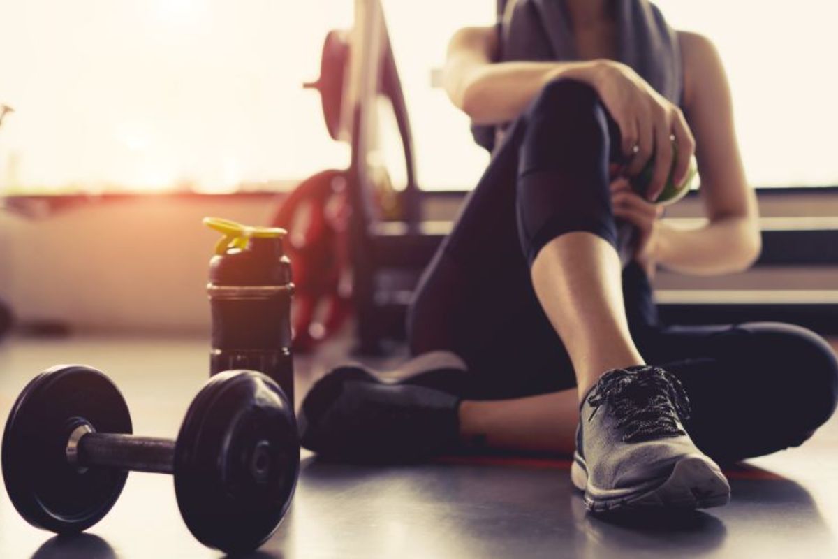 npl-supplements-woman-exercise-workout-in-gym-fitness-breaking-relax-holding-apple-fruit-after-training-sport-min