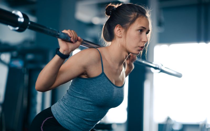 (best-whey-protein-south-africa)-young-sports-woman-doing-squats-with-barbell-in-the-gym-min